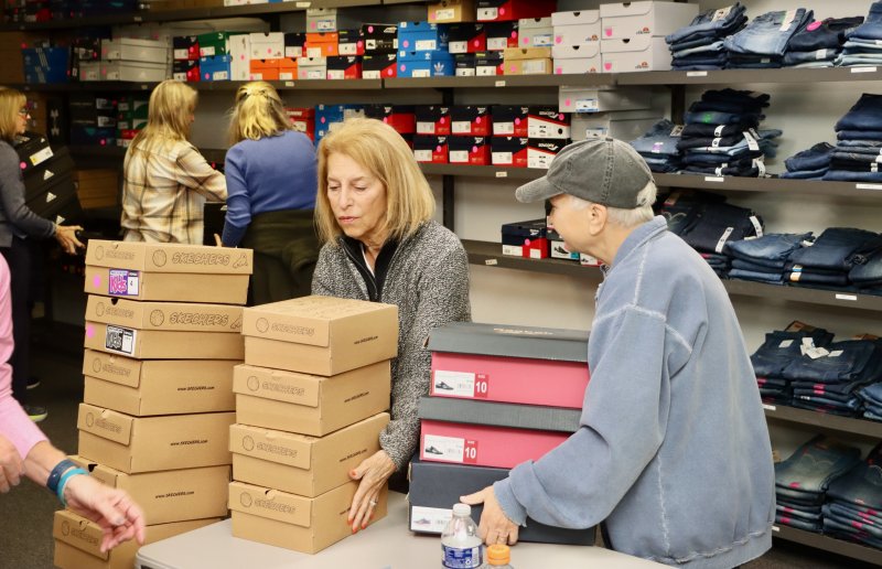 Maria Passero, left, and Deb Quinton stack boxes of new sneakers.